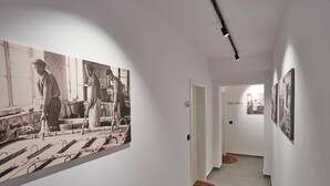 Un pasillo con paredes blancas, fotografías en blanco y negro y una lámpara.
