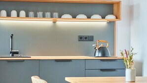 Una cocina moderna con encimera de madera, un hervidor y una repisa con tazas.