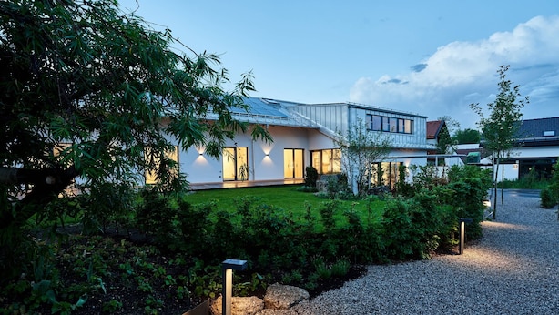 Een modern huis met een verzorgde tuin, een grindpad en een metalen hek.
