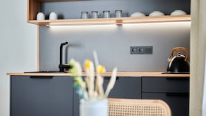 Een moderne keuken met een houten aanrecht, een waterkoker en een vaas met bloemen.