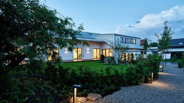 A modern house with a well-maintained garden, a gravel driveway, and a metal fence. - Guesthouse 'Alte Seifensiederei – Viktor' with Shared Terrace, Garden & Wi-Fi (Bad Tölz)