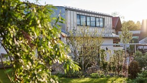 A modern house with a large window, surrounded by greenery and a clear sky. - Guesthouse 'Alte Seifensiederei – Viktor' with Shared Terrace, Garden & Wi-Fi (Bad Tölz)