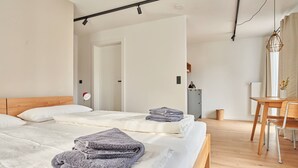 A modern bedroom with two beds, a wooden headboard, a desk with a chair, and a hanging light fixture. - Guesthouse 'Alte Seifensiederei – Viktor' with Shared Terrace, Garden & Wi-Fi (Bad Tölz)