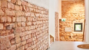Un pasillo con paredes de ladrillo visto y una pared de piedra al fondo.