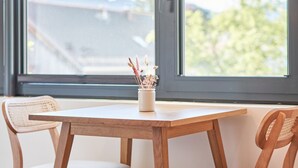 Una mesa de comedor de madera con dos sillas, una lámpara colgante y una ventana con vistas al exterior.