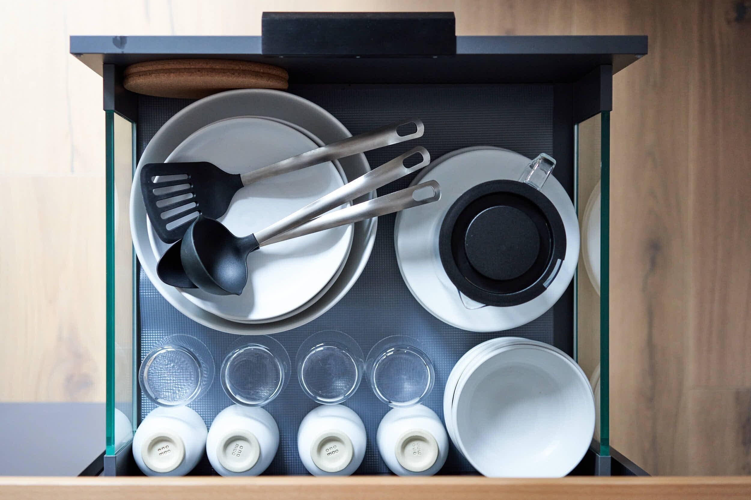 Un cajón de cocina con utensilios, platos y cristalería.