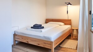 Un dormitorio con una cama de madera, una lámpara de noche y una ventana con cortinas.