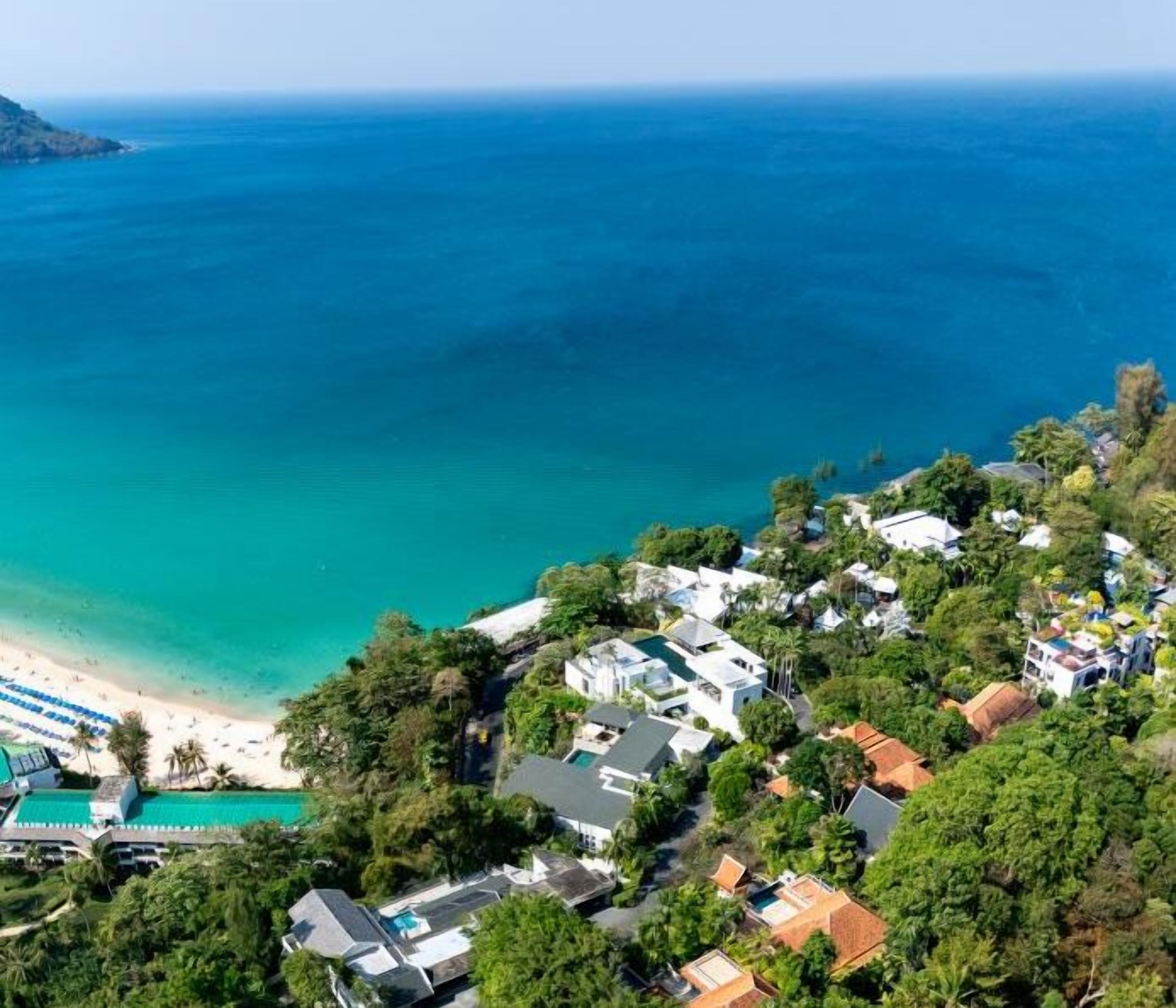 A coastal residential area with houses, a beach, and a clear view of the ocean.