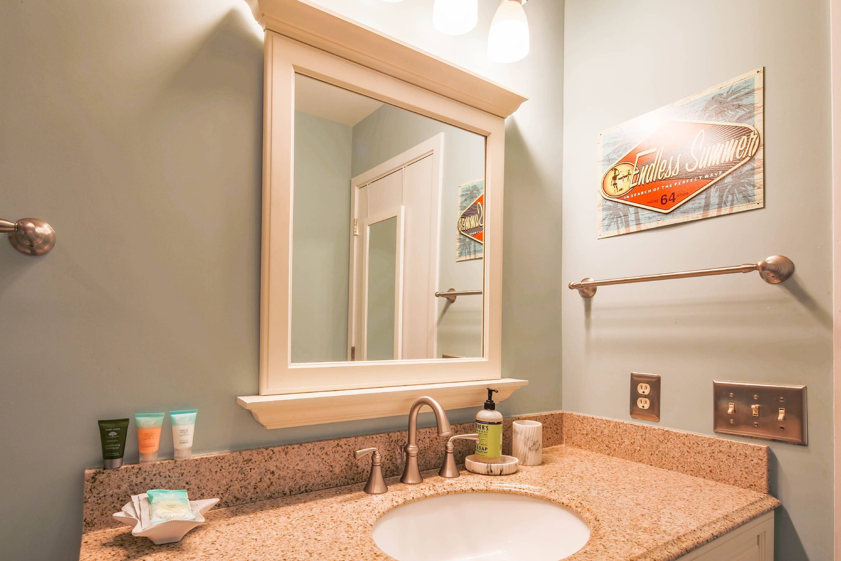 A bathroom with a sink, mirror, and toiletries.