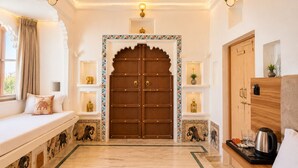 A hotel lobby with a large wooden door, a seating area with cushions, and a coffee station. - Amoraya — A Lake View Heritage Haveli (Old City Udaipur) (Udaipur)