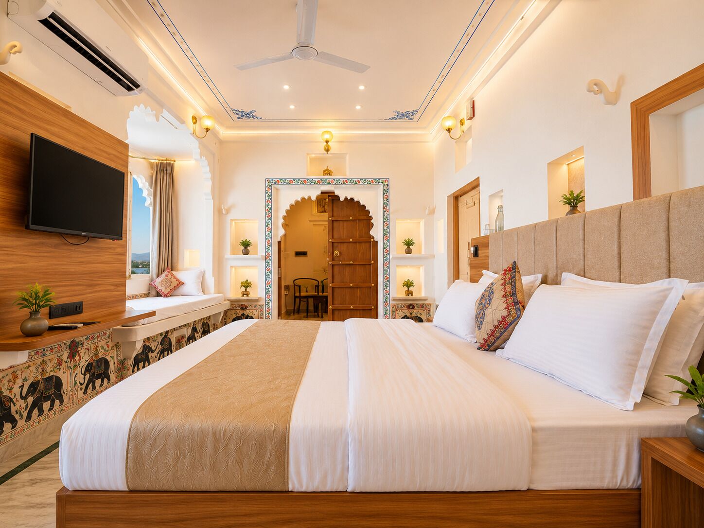 Een goed verlichte slaapkamer met een groot bed, een flatscreen televisie, een plafondventilator en een decoratieve wand.