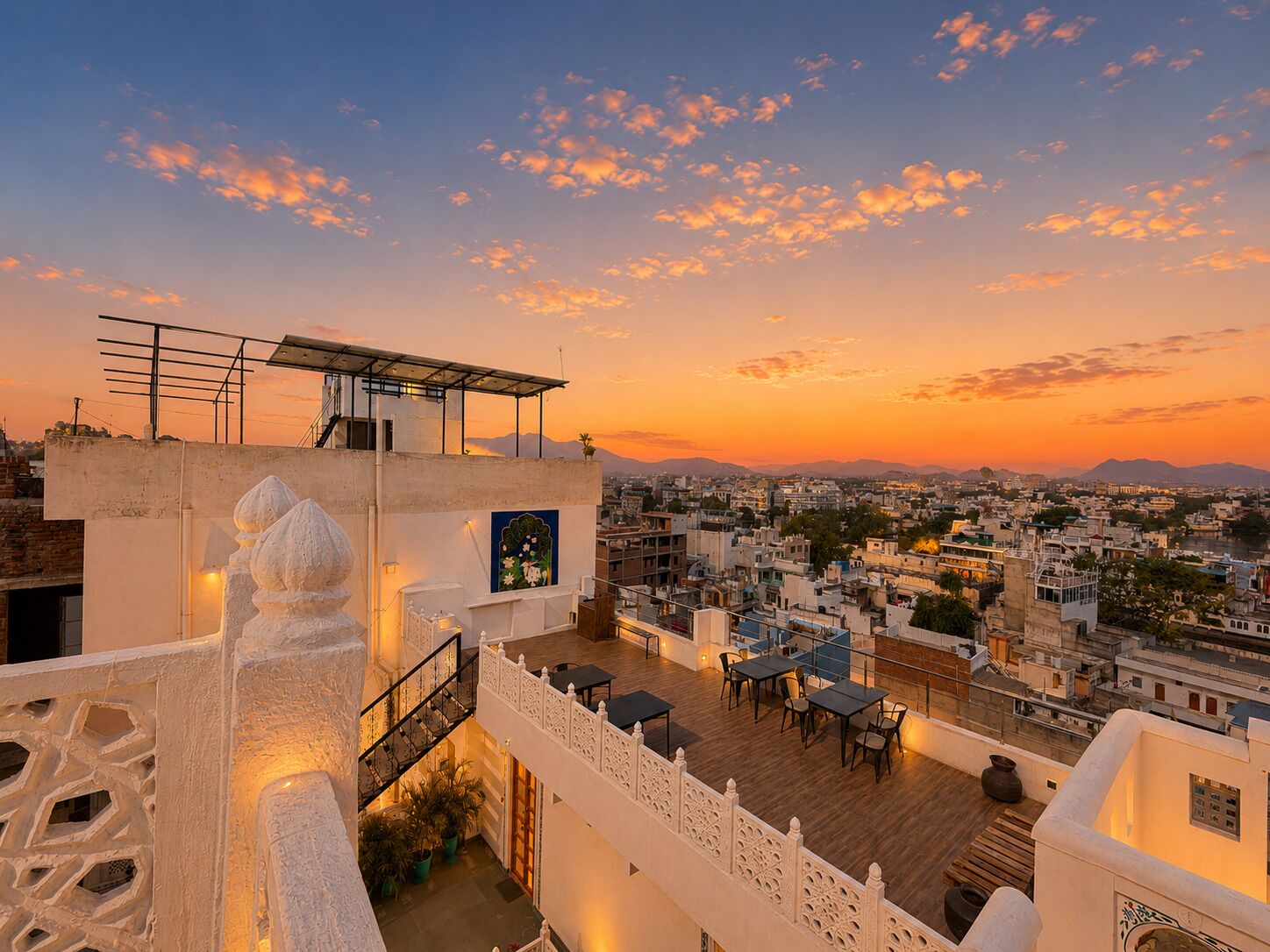 Une terrasse sur le toit avec des sièges extérieurs, une vue sur le paysage urbain et un coucher de soleil.
