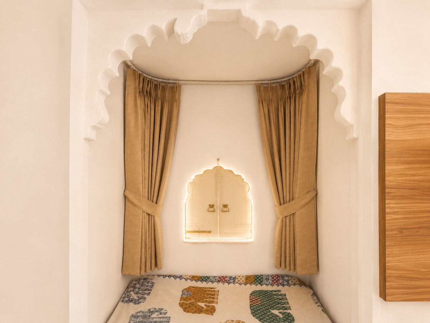 A room with a window, curtains, a bed with a patterned bedspread, and a wooden wall panel.