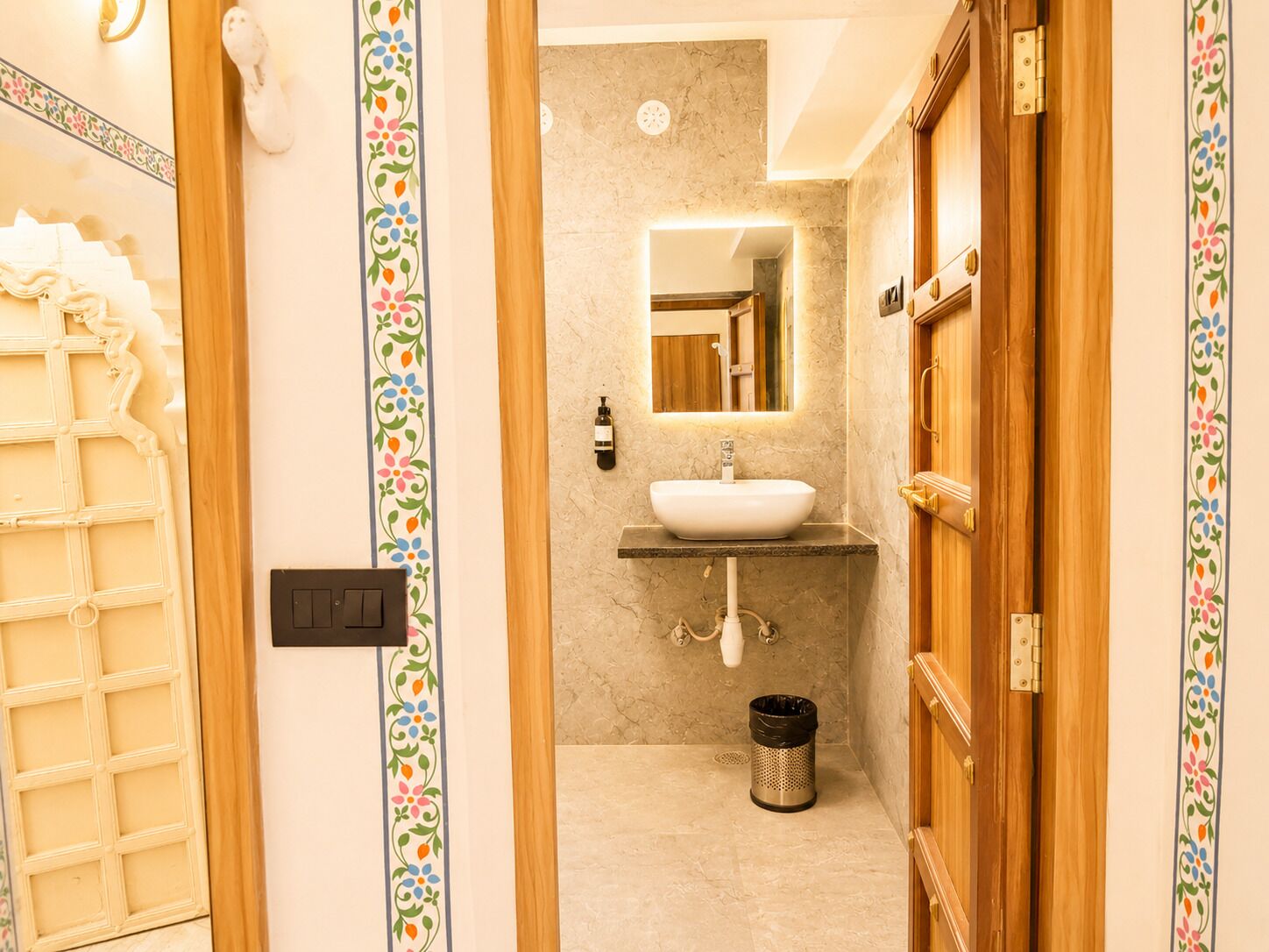 A bathroom with a sink, mirror, and a trash can.