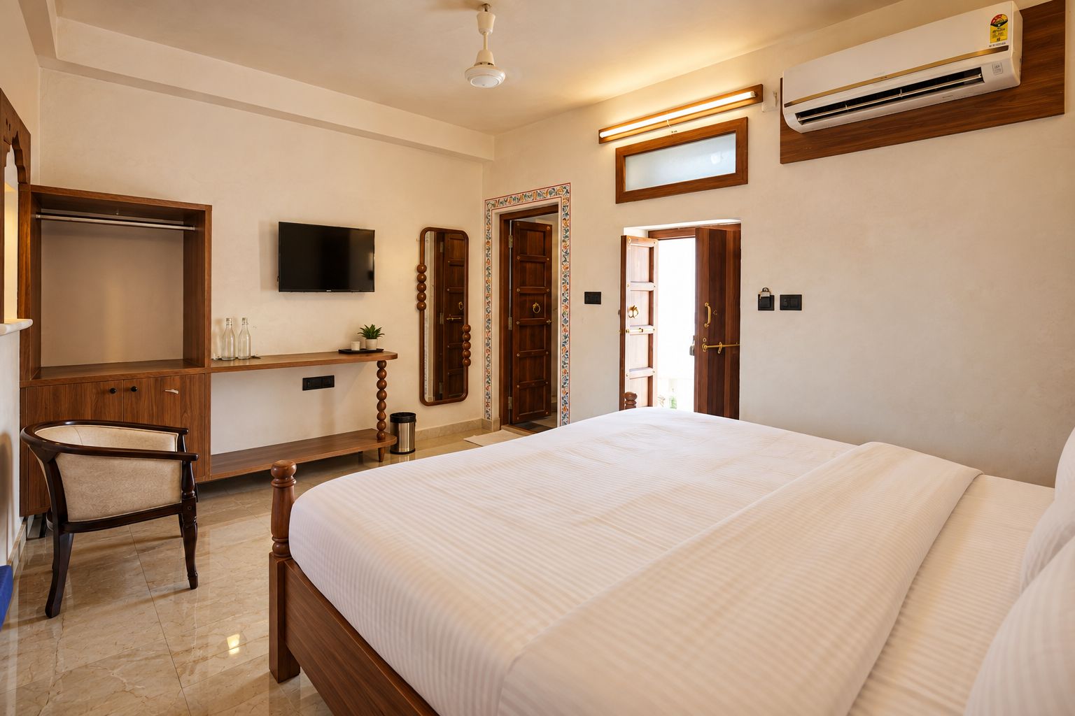 A hotel room with a bed, a desk, a television, and an air conditioning unit.