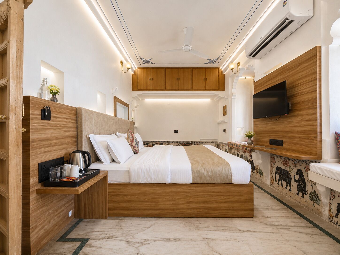 Un dormitorio con cama, mesita de noche, televisor en la pared y ventilador de techo.