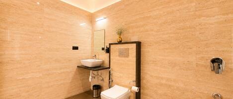 A modern bathroom with a white sink, toilet, and a large mirror.