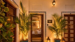 A hotel entrance with a warm interior, potted plants, and a sign reading 'AMORAYA HAVELI'. - Amoraya — A Lake View Heritage Haveli (Old City Udaipur) (Udaipur)