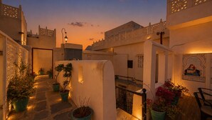 A courtyard with potted plants, a staircase, and a wall with a mural. - Amoraya — A Lake View Heritage Haveli (Old City Udaipur) (Udaipur)