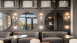 Ein moderner Lounge-Bereich mit runden Sitzgelegenheiten, einem großen Spiegel und Wandleuchten.