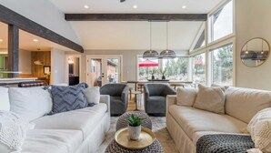 A spacious living area with a high ceiling, large windows, and a modern kitchen in the background. - The Gem Estate by Avantstay Modern Farmhouse w/ Lavender Fields + Hot Tub (Bend)