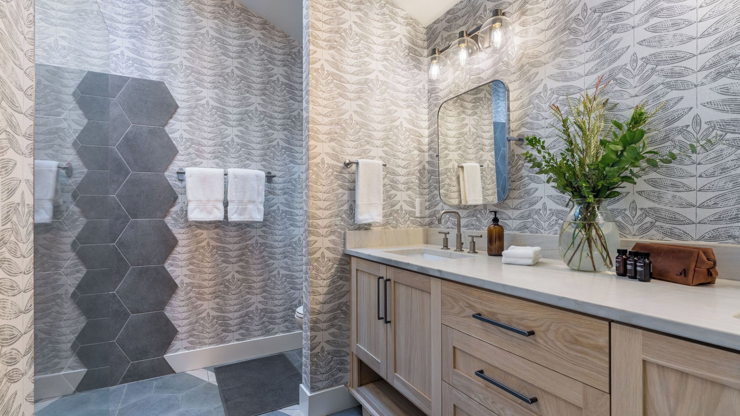 Un bagno moderno con doccia, lavabo con specchio e mobili in legno.