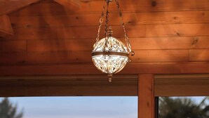 A wooden interior with a round table set for dining, two chairs, and a hanging light fixture. - Dolphin House Oceanview Family Getaway (Nanoose Bay)