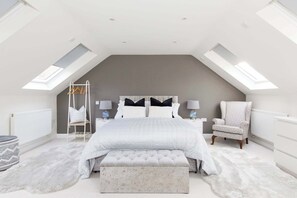A bedroom with a large bed, a chair, a bench, and a ladder.