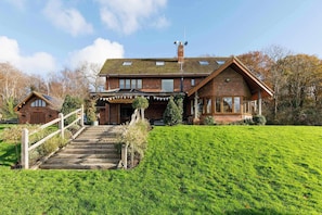 A two-story brick house with a sloped roof, a front porch with a railing, and a small staircase leading to the entrance. - Serene Riverside: 6BR Luxury Retreat in Curdridge (Curdridge)