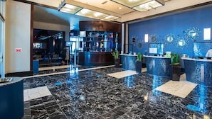 Un moderno vestíbulo de hotel con suelo de mármol, mostradores de recepción y decoración mural.