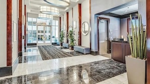Un moderno hall de hotel con suelo de mármol, ventanas amplias y una recepción.