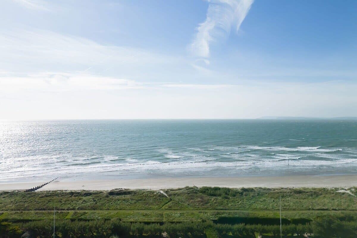 A coastal landscape with a beach and grassy areas in the foreground.