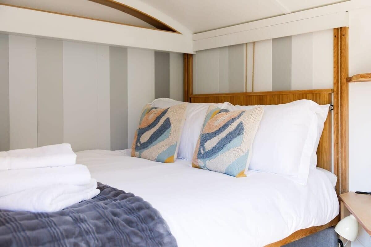 A neatly made bed with a striped headboard, a bedside table with a lamp, and a folded towel on the bed.