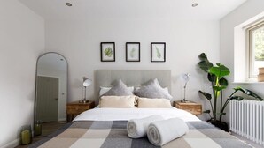 A modern bedroom with a large bed, a headboard, bedside tables, a mirror, and framed botanical prints on the wall. - Stylish Self-Contained Countryside Accommodation (Funtington)