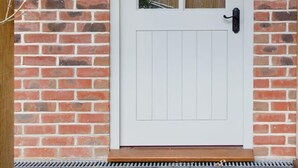 A white door with a glass panel, set in a brick wall with a wooden door frame. - Stylish Self-Contained Countryside Accommodation (Funtington)