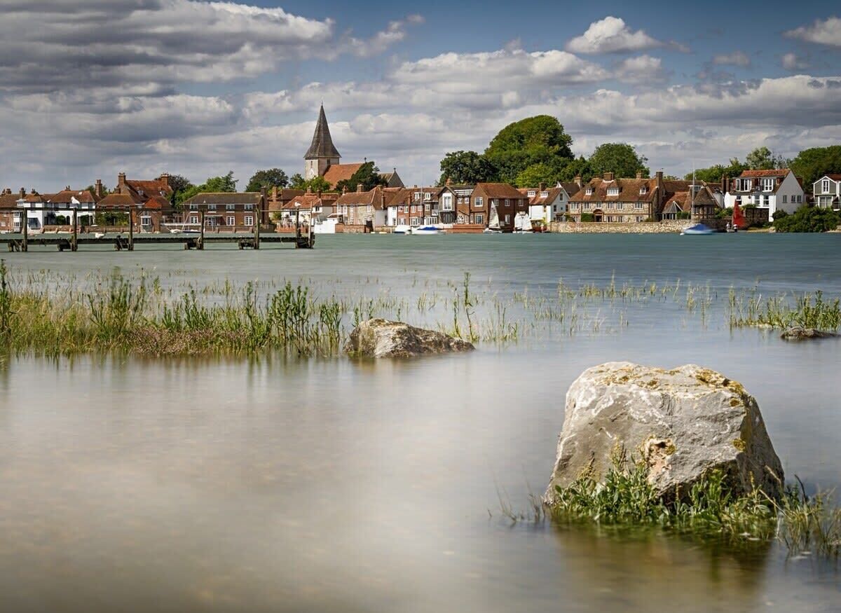 A calm waterfront with traditional buildings and a prominent church steeple.