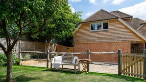 A wooden house with a brick exterior, a wooden fence, and a bench in the yard. - Stylish Self-Contained Countryside Accommodation (Funtington)
