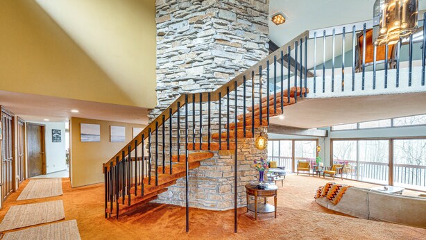 A spacious interior with a stone staircase, a large window, and a cozy seating area. - Eclectic Hubertus Home w/ Game Room & Fire Pit! (Hubertus)