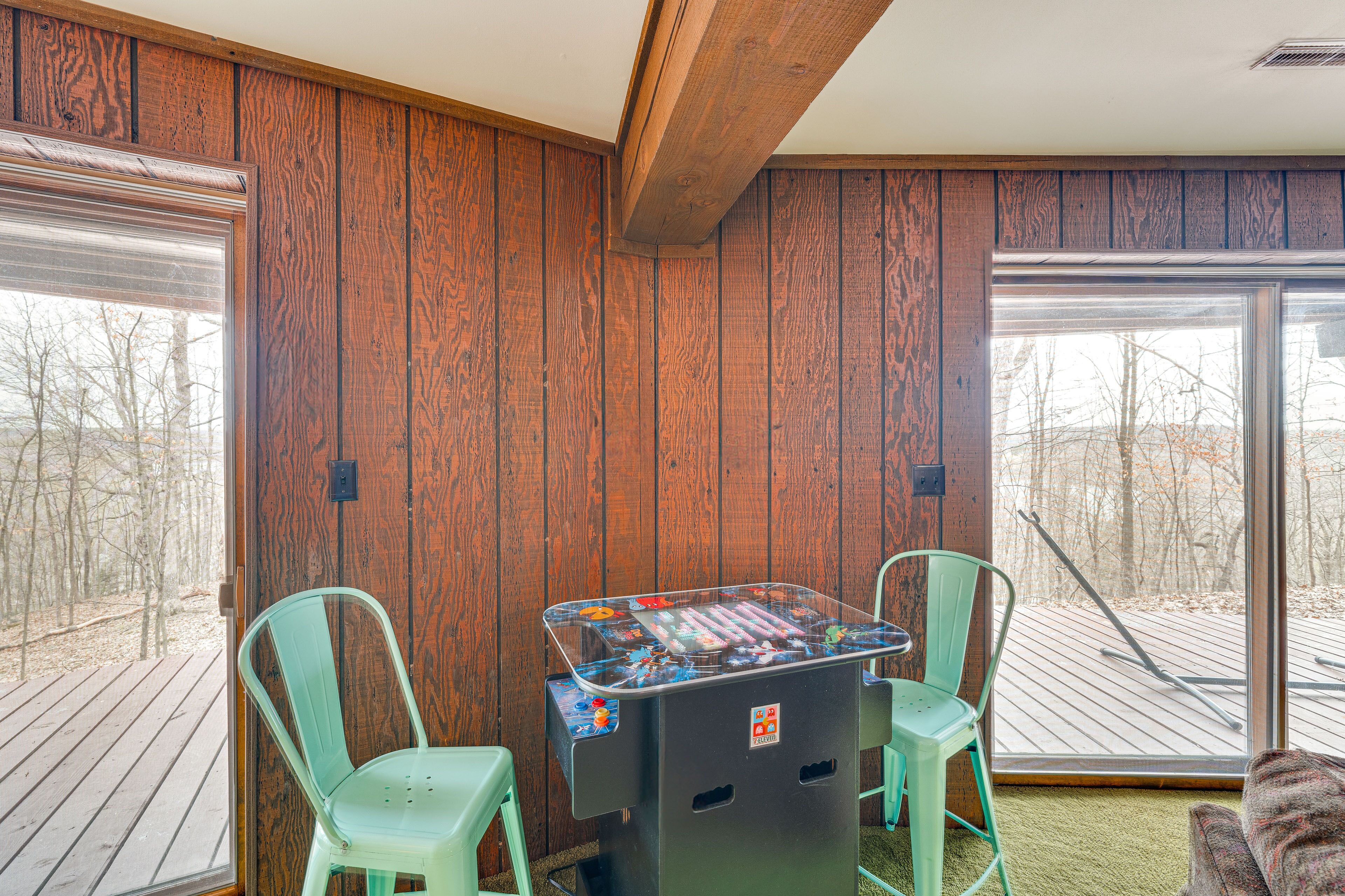 A room with wooden walls, a large window, and a foosball table.