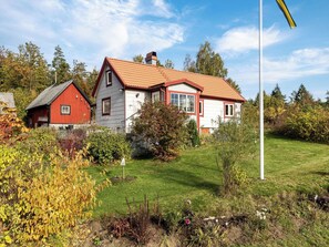 A two-story house with a red and white exterior, a red roof, and a well-maintained garden with various plants and a flagpole. - Skjutsmåla by Interhome (Olofström)