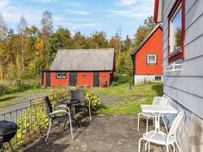 A patio with outdoor furniture, a red barn, and a grey building with a window. - Skjutsmåla by Interhome (Olofström)