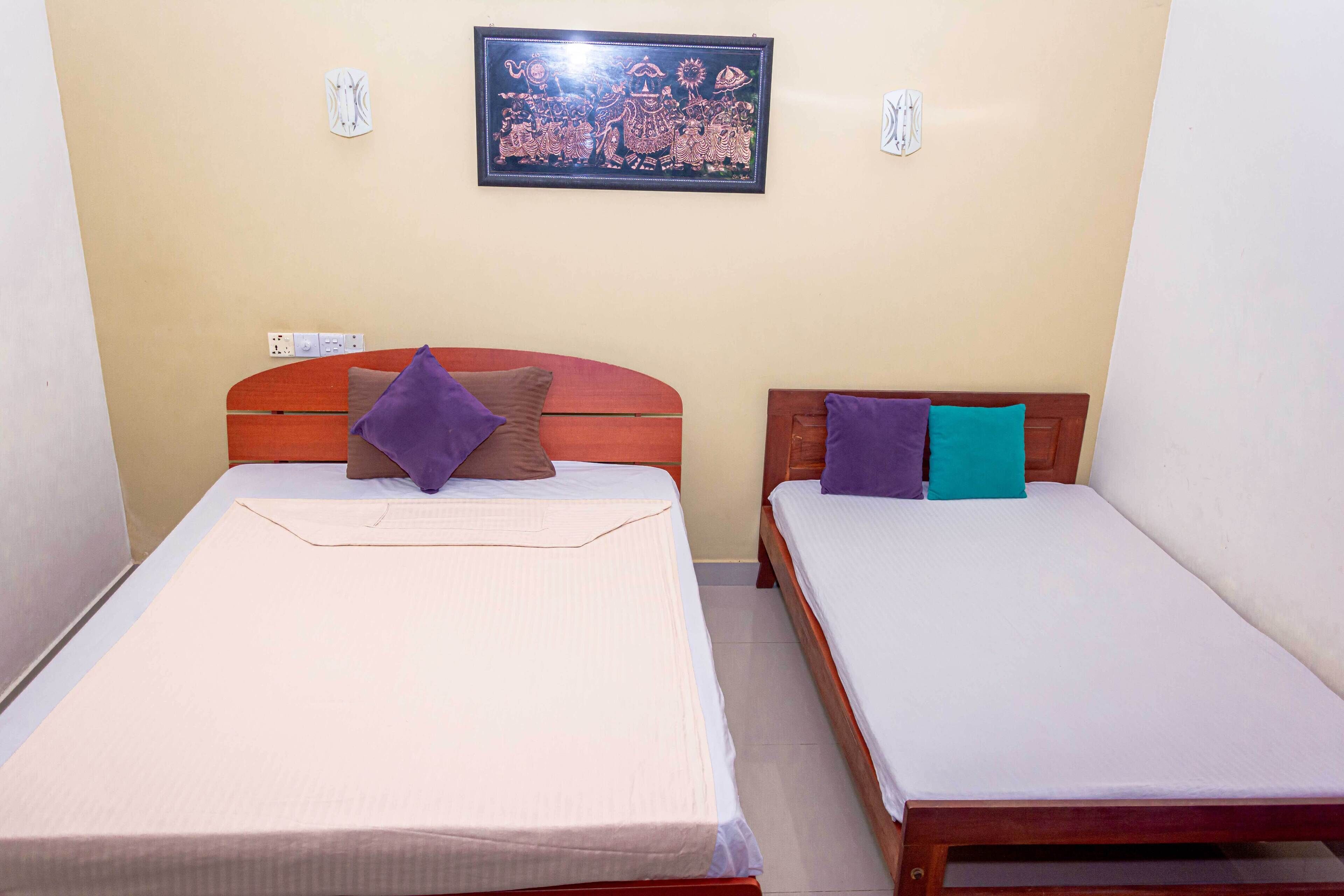 Two single beds with wooden headboards, a wall-mounted picture, and a small table between them.