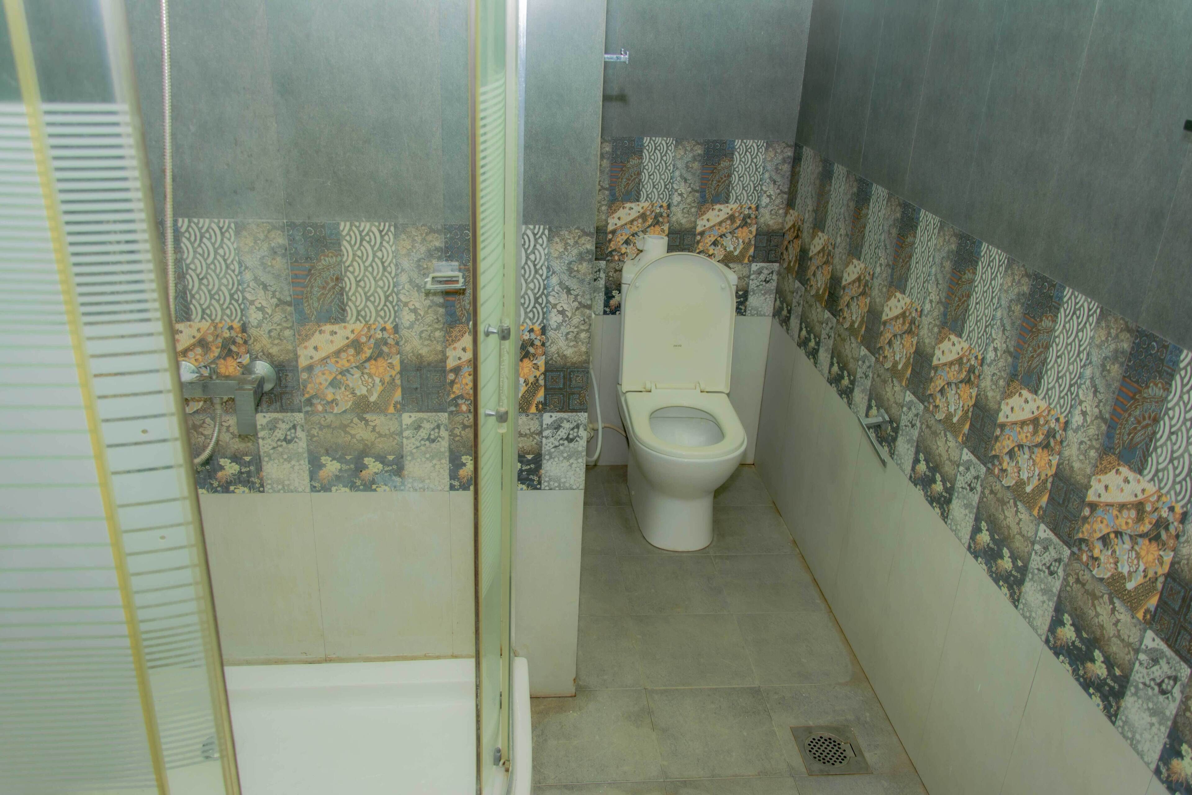 Un baño con inodoro, ducha y paredes de azulejos.