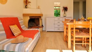 A cozy living room with a fireplace, a dining area with wooden furniture, and a bed with striped bedding.