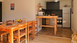 A compact kitchen with modern appliances, a dining area with wooden furniture, and a small island with a microwave.