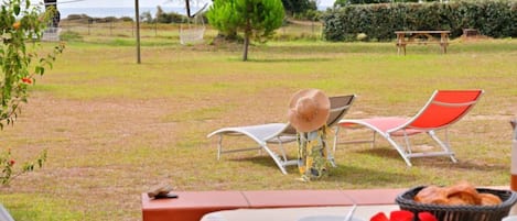 An outdoor dining area with a table set for two, a basket of bread, and a view of the surrounding landscape.