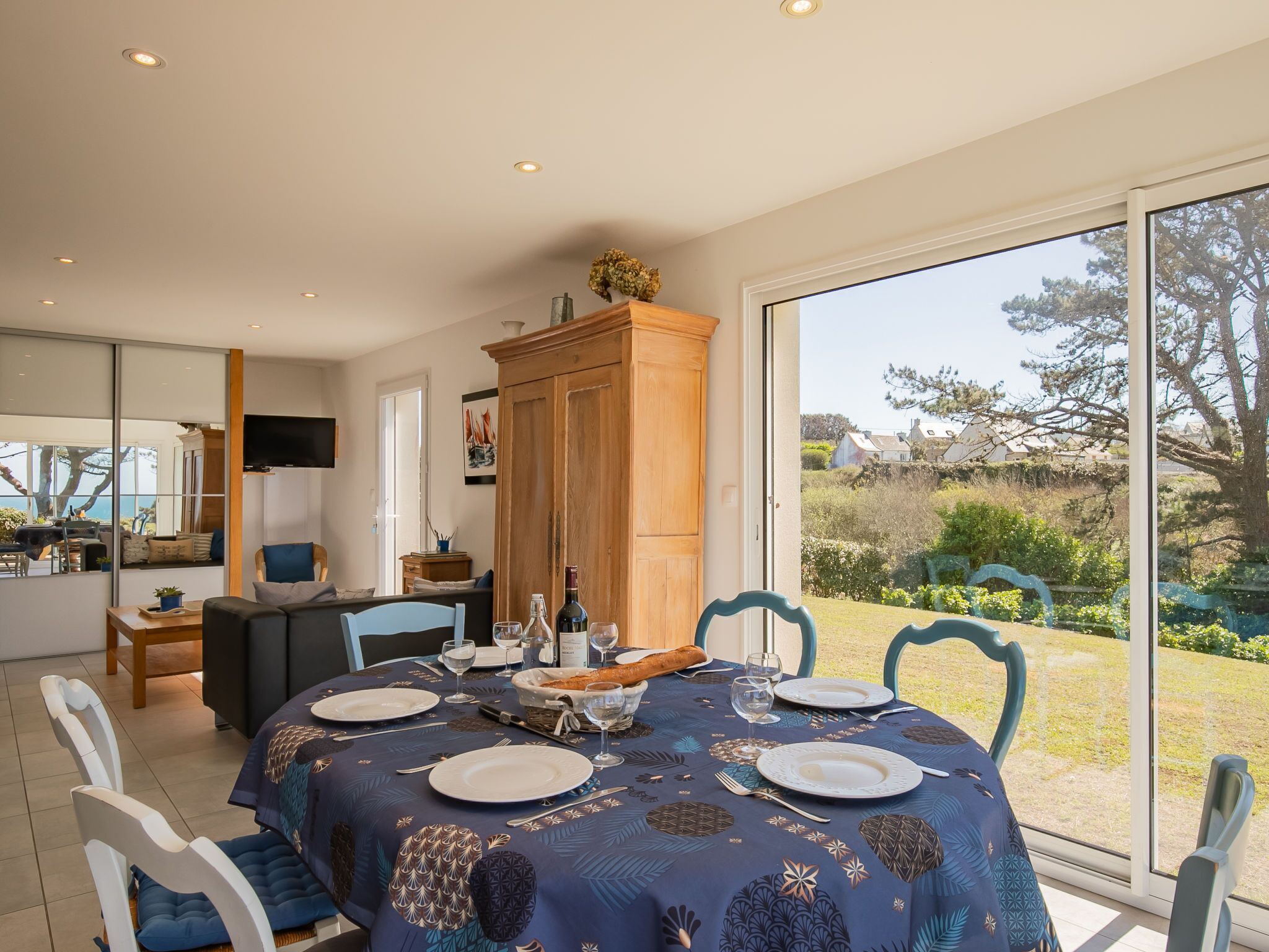 A dining area with a table set for four, a wooden cabinet, and a view of the outdoors.