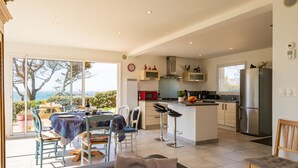 Uma cozinha moderna com ilha central, banquetas e área de refeições com vista.
