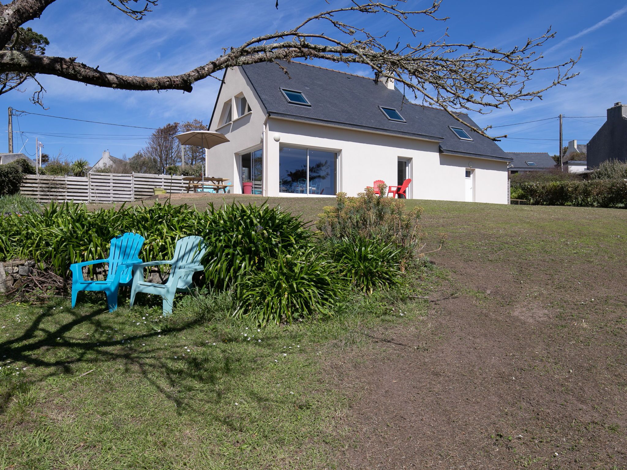 Uma casa moderna com telhado inclinado, grandes janelas e uma área de varanda coberta.