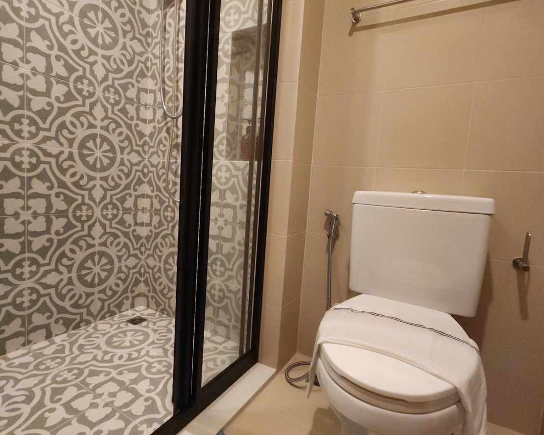 Casa de banho com azulejos estampados, sanita e zona de duche.